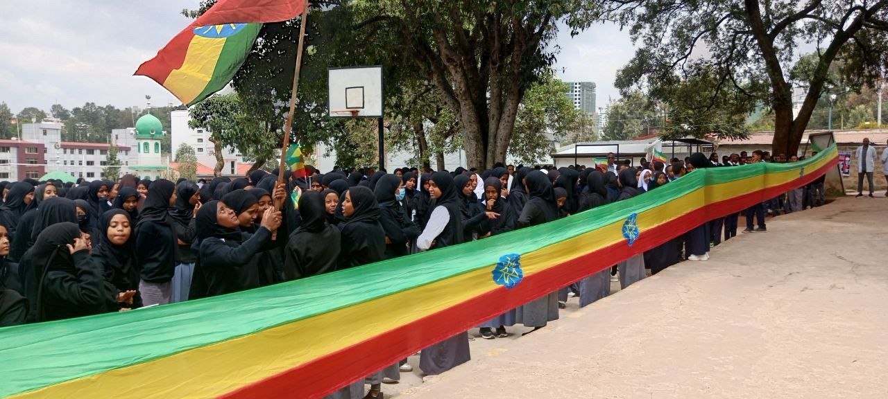 Mekanisa Abadir School students and staff hold a large Ethiopian flag banner during the Woreda Flag Day celebration.