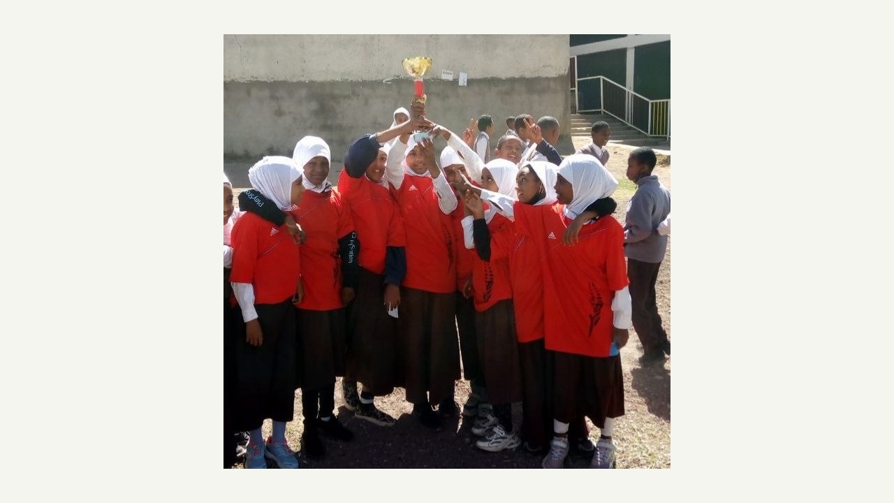 Grade 5 girls celebrate with the football championship trophy